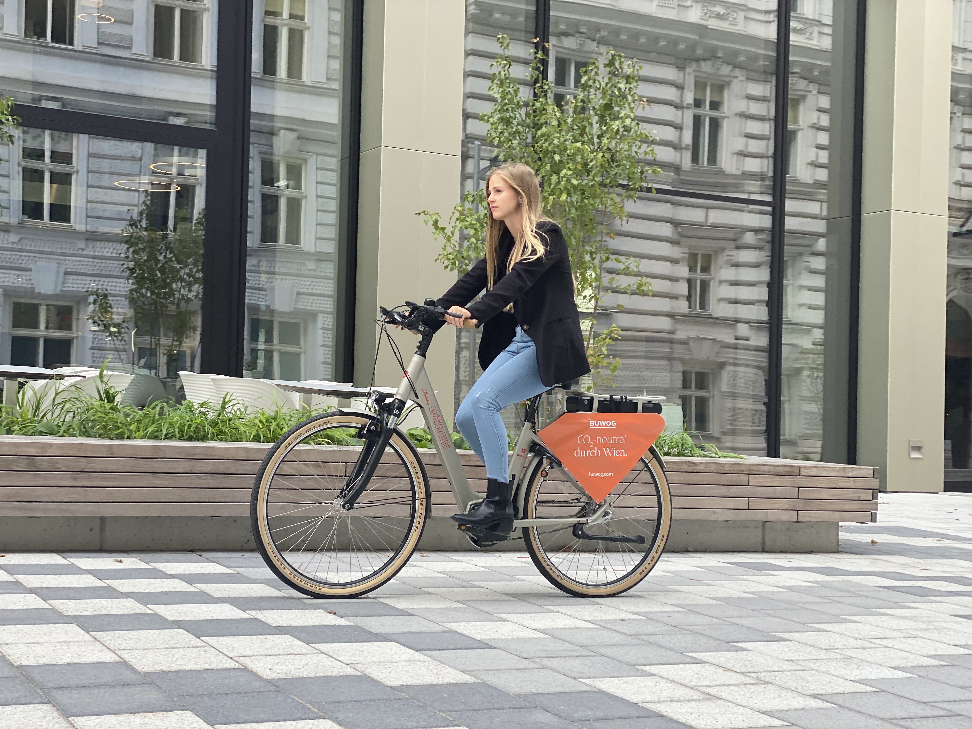 Eine Frau fährt auf einem BUWOG Fahrrad durch Wien.