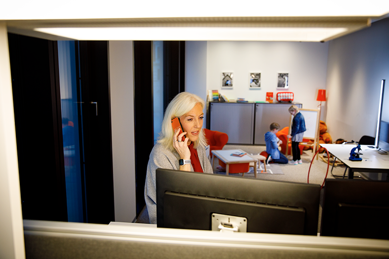 Mitarbeiterin arbeitet mit Kindern im Hintergrund